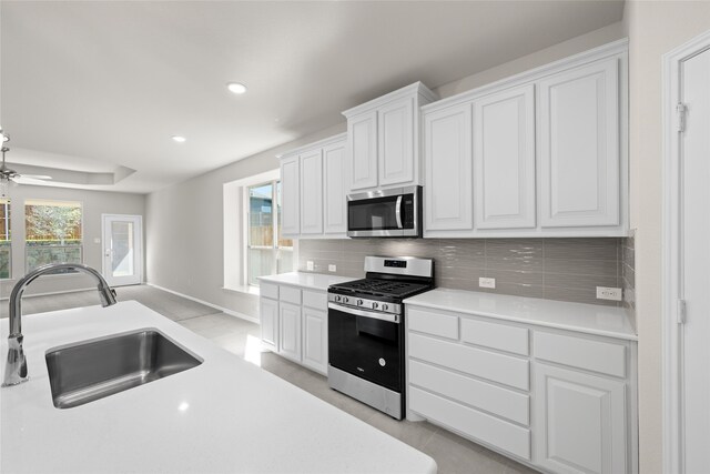 kitchen featuring white cabinets, sink, stainless steel appliances, and an island with sink