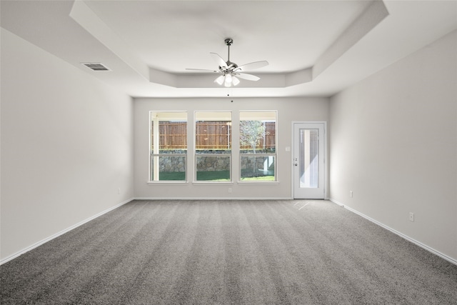 carpeted spare room featuring ceiling fan and a tray ceiling