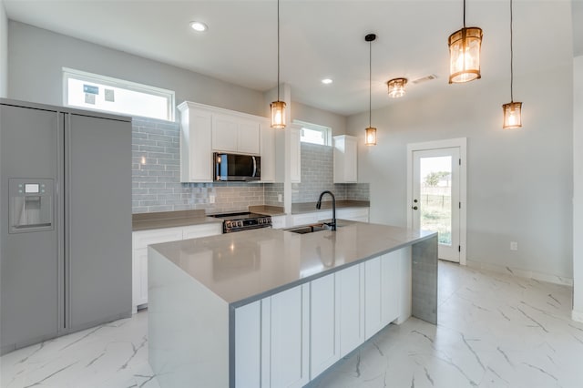 kitchen featuring appliances with stainless steel finishes, hanging light fixtures, sink, and a wealth of natural light