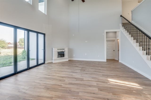 unfurnished living room with a towering ceiling, light hardwood / wood-style floors, and a wealth of natural light