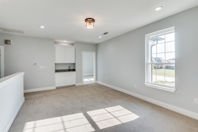 unfurnished living room featuring light colored carpet and sink