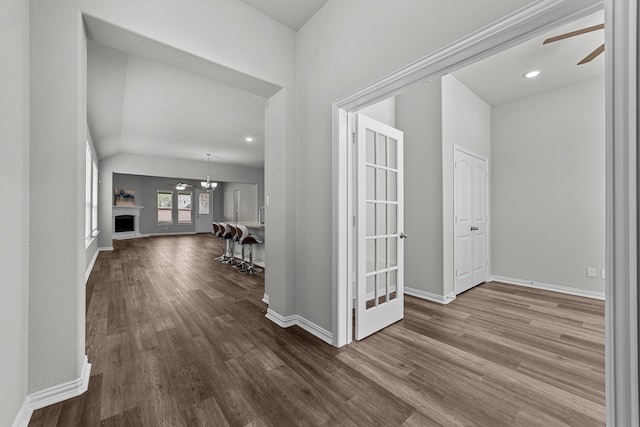 hallway featuring lofted ceiling, hardwood / wood-style floors, and a chandelier