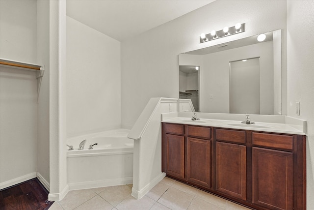 bathroom with a tub to relax in, vanity, and tile patterned floors