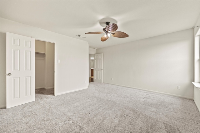 unfurnished bedroom featuring ceiling fan, a walk in closet, a closet, and light carpet