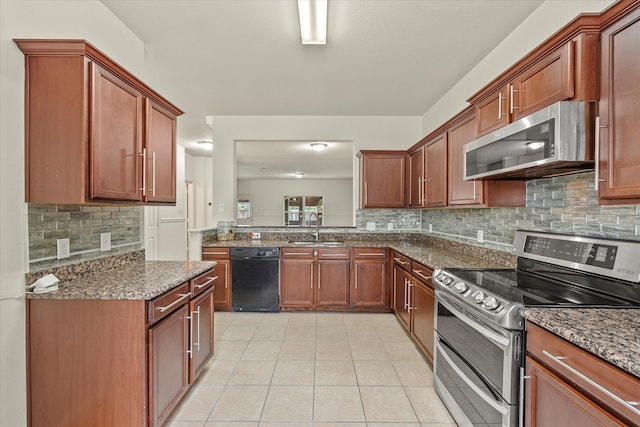 kitchen with light tile patterned floors, backsplash, appliances with stainless steel finishes, sink, and dark stone countertops