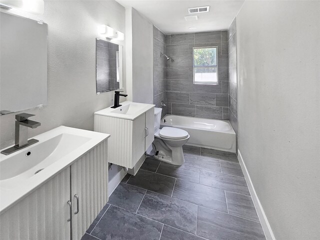 full bathroom featuring vanity, tiled shower / bath, and toilet