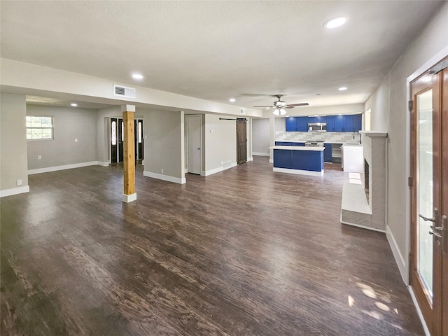 unfurnished living room featuring dark hardwood / wood-style flooring and a barn door