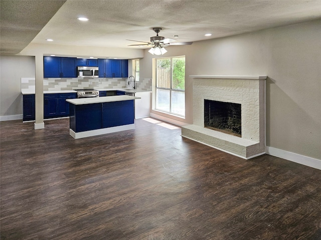 kitchen with stainless steel appliances, dark wood-type flooring, blue cabinets, tasteful backsplash, and a textured ceiling