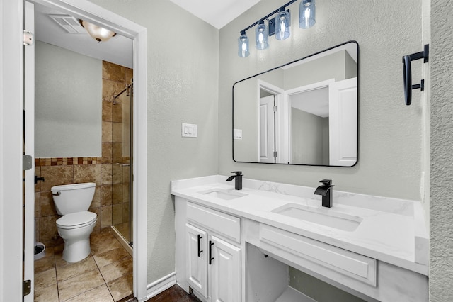 bathroom with vanity, walk in shower, tile patterned flooring, tile walls, and toilet