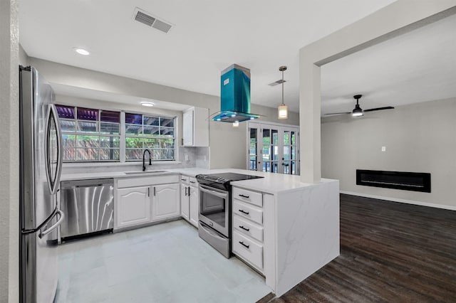 kitchen with stainless steel appliances, kitchen peninsula, sink, ceiling fan, and white cabinets