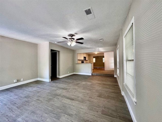 unfurnished living room with dark hardwood / wood-style flooring, ceiling fan, and a textured ceiling