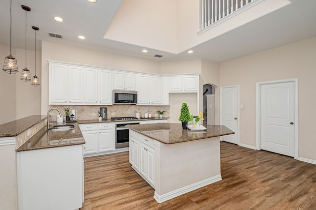 kitchen with stainless steel appliances, white cabinets, kitchen peninsula, and sink