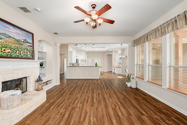 unfurnished living room featuring a fireplace, dark hardwood / wood-style flooring, ceiling fan, and built in shelves