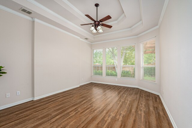 empty room with ceiling fan, a tray ceiling, crown molding, and dark hardwood / wood-style floors