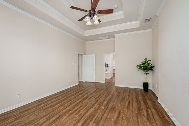 spare room featuring ceiling fan, a tray ceiling, crown molding, and dark wood-type flooring