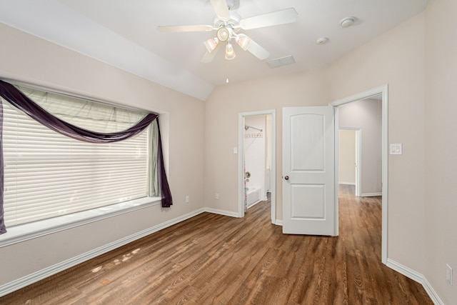 unfurnished bedroom featuring vaulted ceiling, a spacious closet, a closet, wood-type flooring, and ceiling fan