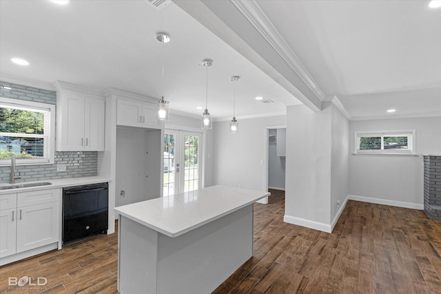 kitchen featuring black dishwasher, sink, hanging light fixtures, and white cabinets