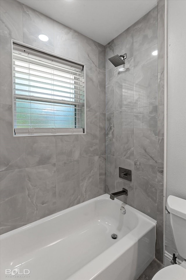 bathroom featuring tiled shower / bath and toilet