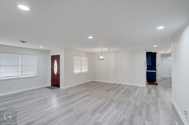 unfurnished living room with an inviting chandelier and light wood-type flooring