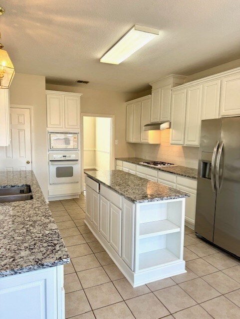 kitchen with appliances with stainless steel finishes, a center island, decorative backsplash, and sink