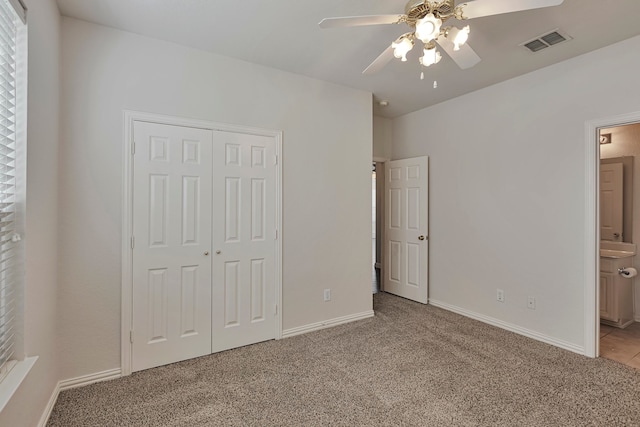 unfurnished bedroom with light carpet, ensuite bathroom, ceiling fan, and a closet