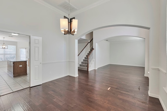 empty room with wood-type flooring, crown molding, and a notable chandelier