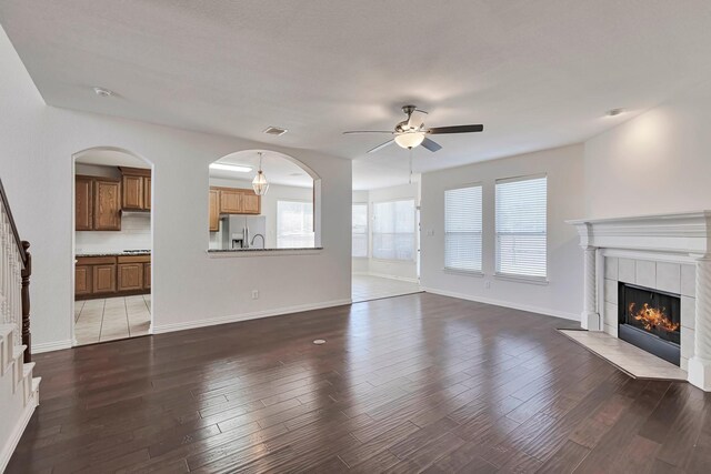 unfurnished living room with ceiling fan, dark hardwood / wood-style flooring, and a fireplace