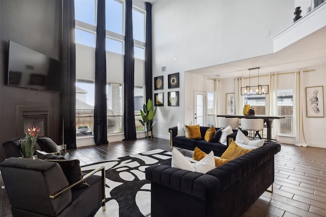 living room with plenty of natural light, a towering ceiling, and dark wood-type flooring