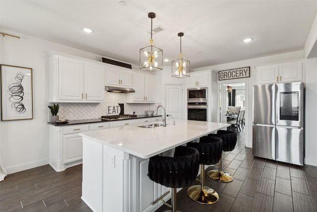 kitchen with white cabinetry, sink, a kitchen island with sink, and appliances with stainless steel finishes