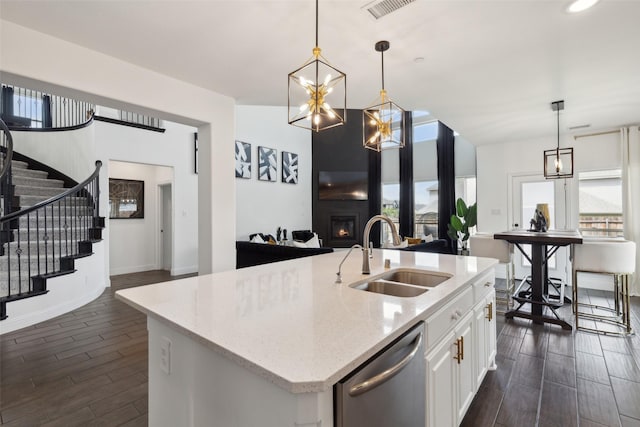 kitchen featuring white cabinets, decorative light fixtures, stainless steel dishwasher, and sink