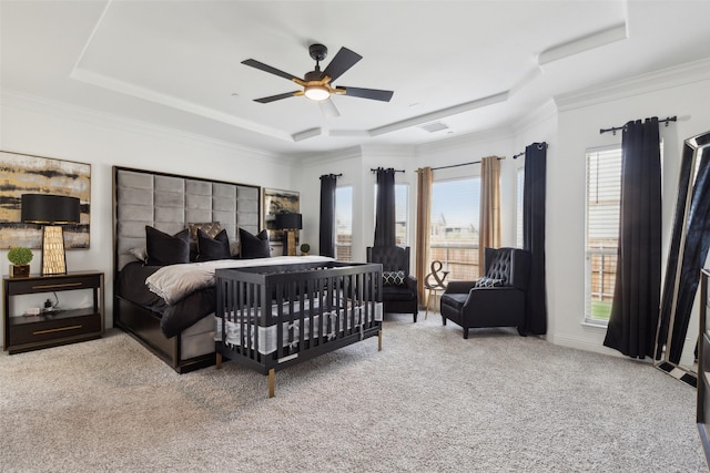 carpeted bedroom featuring a tray ceiling, multiple windows, and ceiling fan