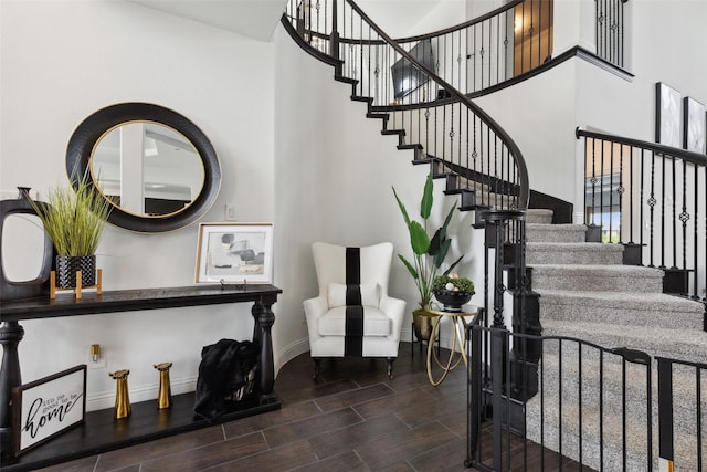 stairway with a towering ceiling and wood-type flooring