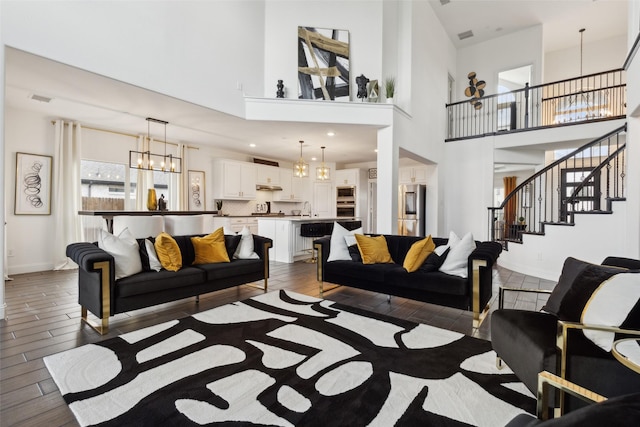 living room featuring dark hardwood / wood-style flooring, an inviting chandelier, a high ceiling, and sink