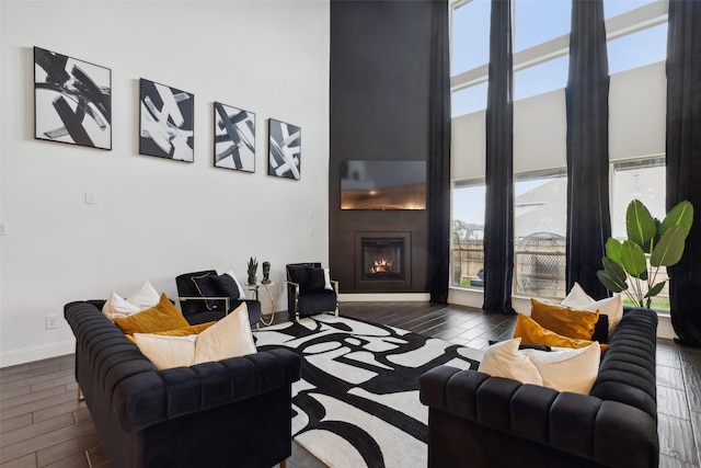 living room featuring a large fireplace, dark hardwood / wood-style flooring, and a high ceiling