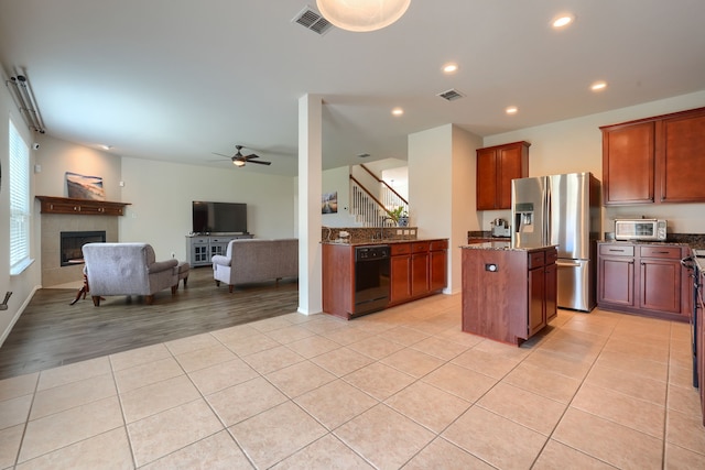 kitchen with a center island, dark stone countertops, black appliances, and sink