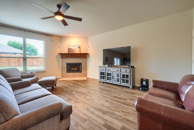 living room with hardwood / wood-style floors, a tiled fireplace, and ceiling fan