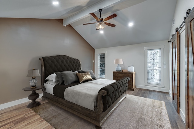 bedroom featuring a barn door, multiple windows, ceiling fan, and dark hardwood / wood-style flooring