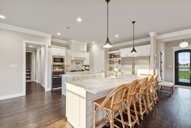 kitchen featuring a large island with sink, white cabinetry, appliances with stainless steel finishes, and pendant lighting