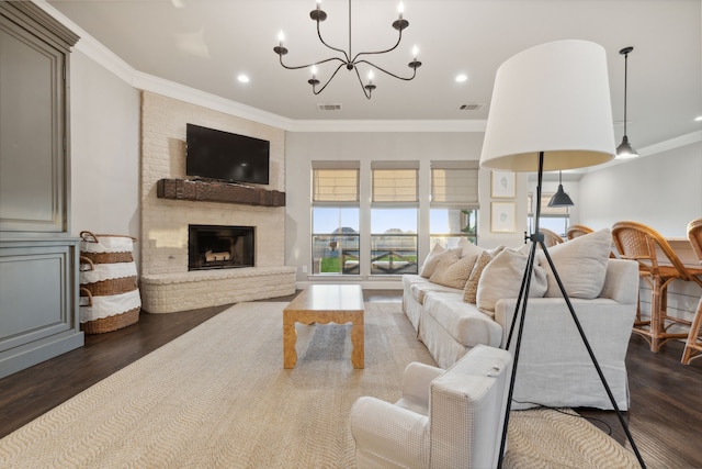 living room featuring crown molding, a chandelier, dark hardwood / wood-style floors, and a brick fireplace