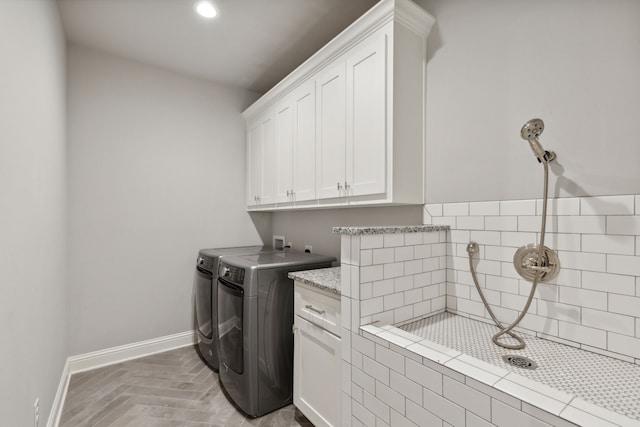 clothes washing area featuring washing machine and clothes dryer and cabinets