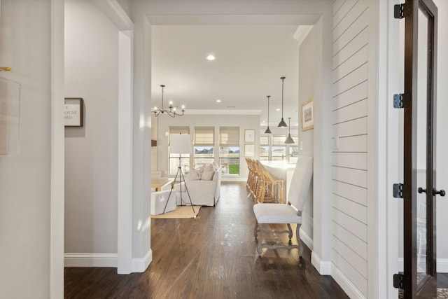 hallway featuring dark hardwood / wood-style floors and an inviting chandelier