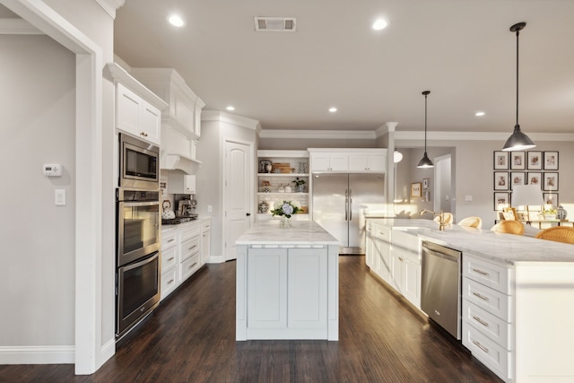 kitchen featuring dark wood-type flooring, pendant lighting, built in appliances, white cabinets, and a center island