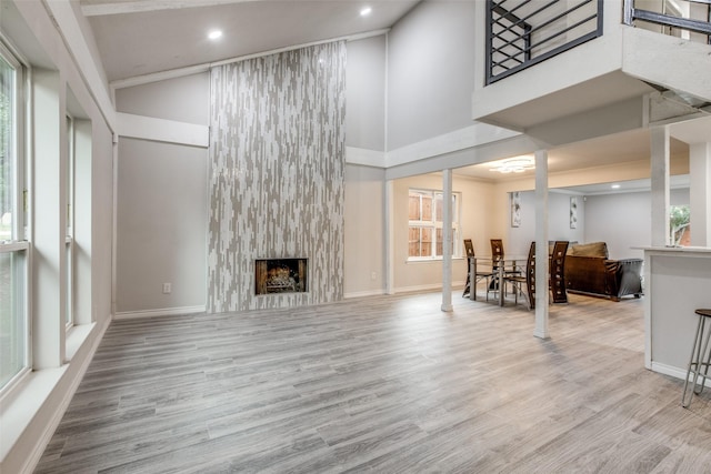 living room with light hardwood / wood-style flooring, a high ceiling, and a fireplace