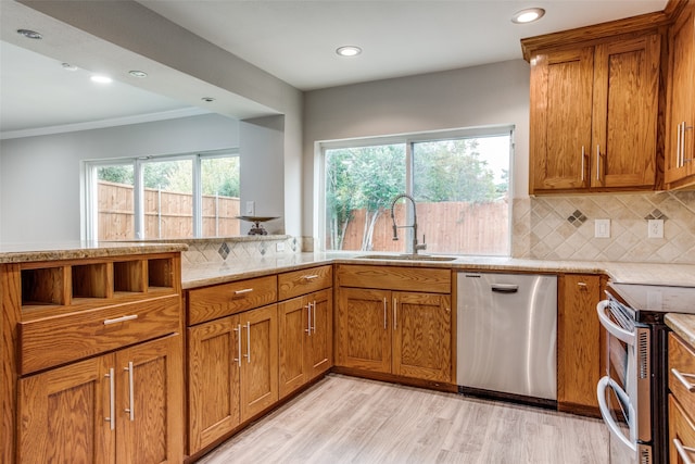 kitchen featuring appliances with stainless steel finishes, light wood-type flooring, backsplash, sink, and plenty of natural light