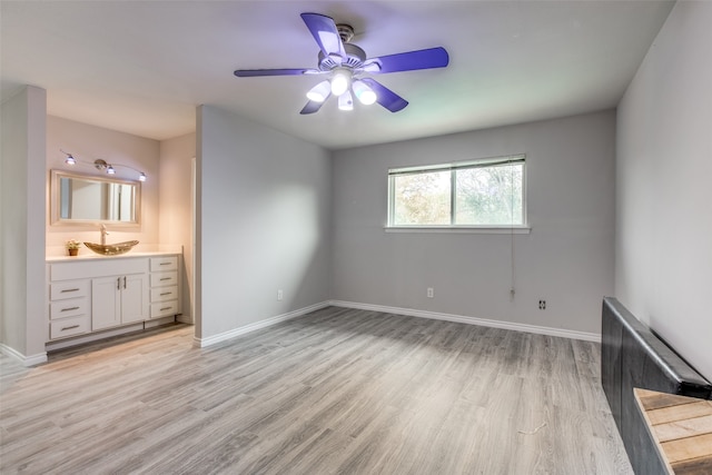 unfurnished bedroom with connected bathroom, light hardwood / wood-style flooring, ceiling fan, and sink