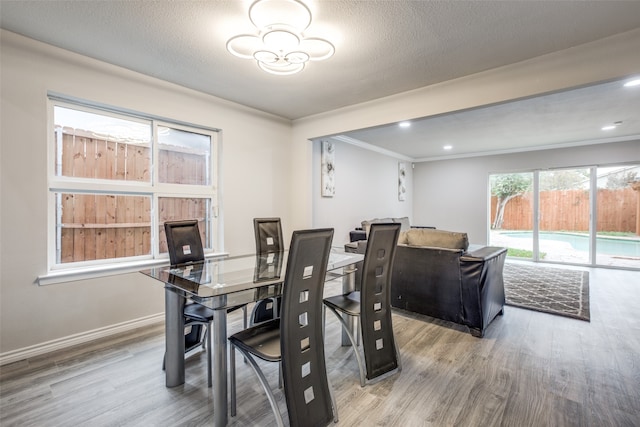 dining room with hardwood / wood-style floors, crown molding, and a textured ceiling