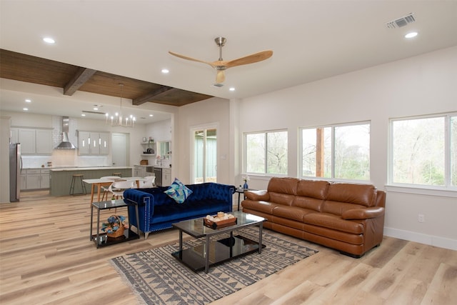 living room featuring a healthy amount of sunlight, beamed ceiling, light hardwood / wood-style floors, and ceiling fan with notable chandelier