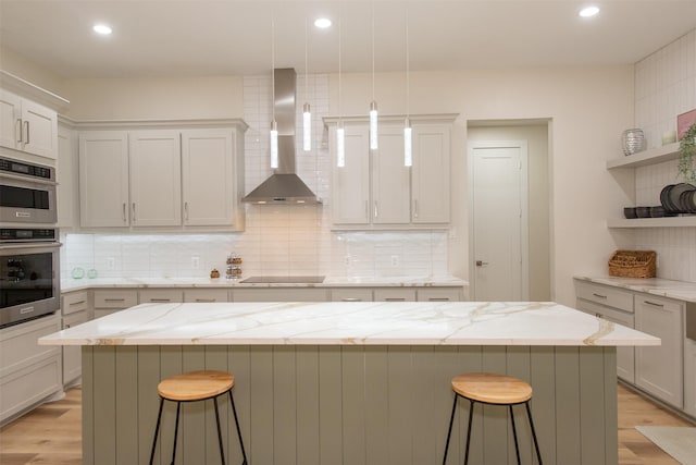 kitchen featuring a center island, wall chimney exhaust hood, and a breakfast bar area