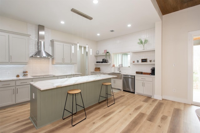 kitchen with dishwasher, a center island, wall chimney range hood, pendant lighting, and a breakfast bar