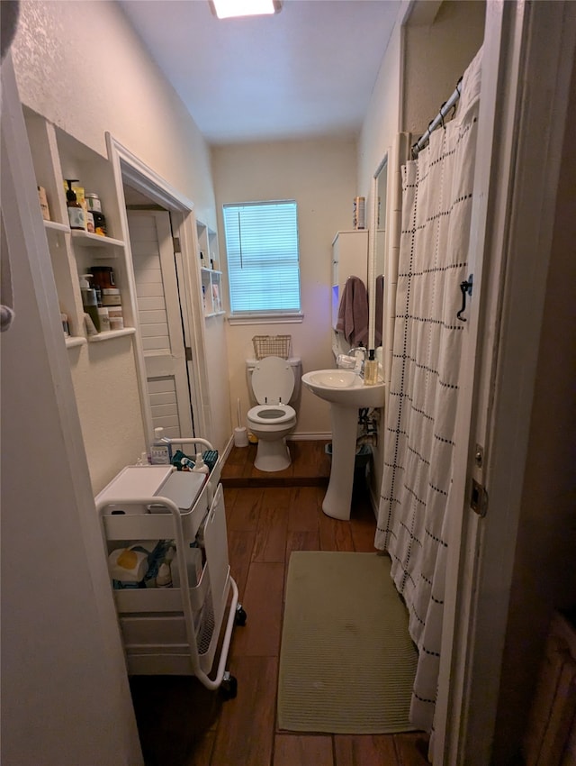 bathroom with hardwood / wood-style floors, walk in shower, toilet, and sink